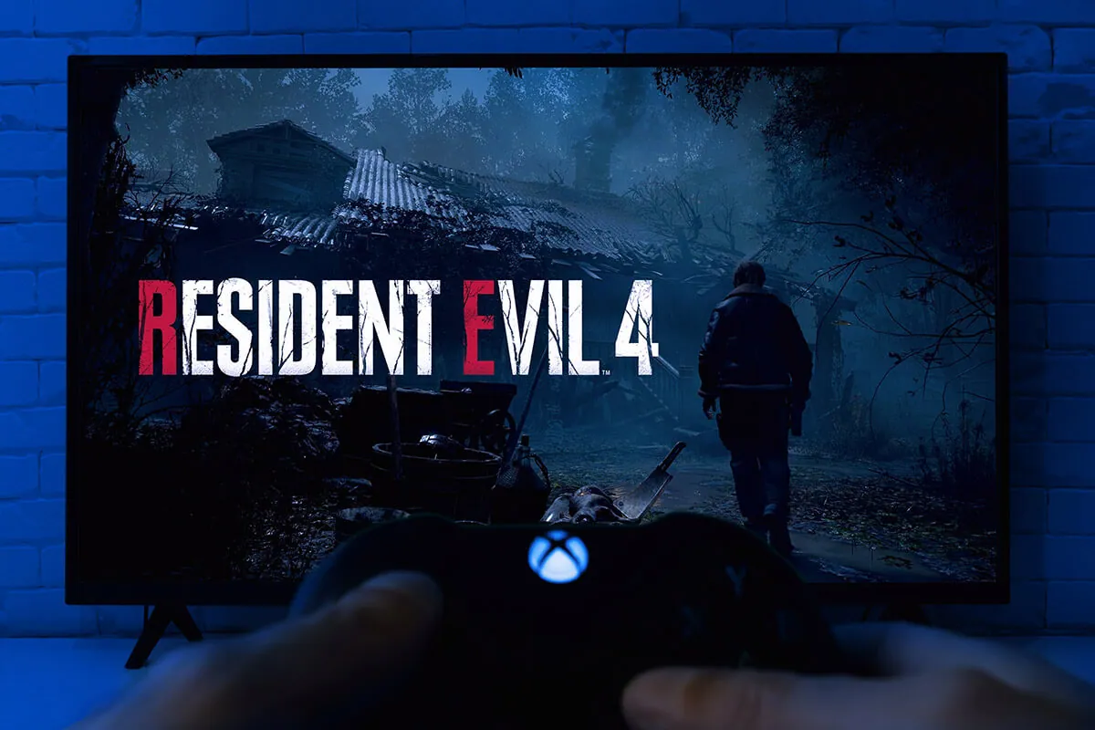Man playing Resident Evil 4 Remake with Xbox controller on TV. Top PC Games To Play With A Controller