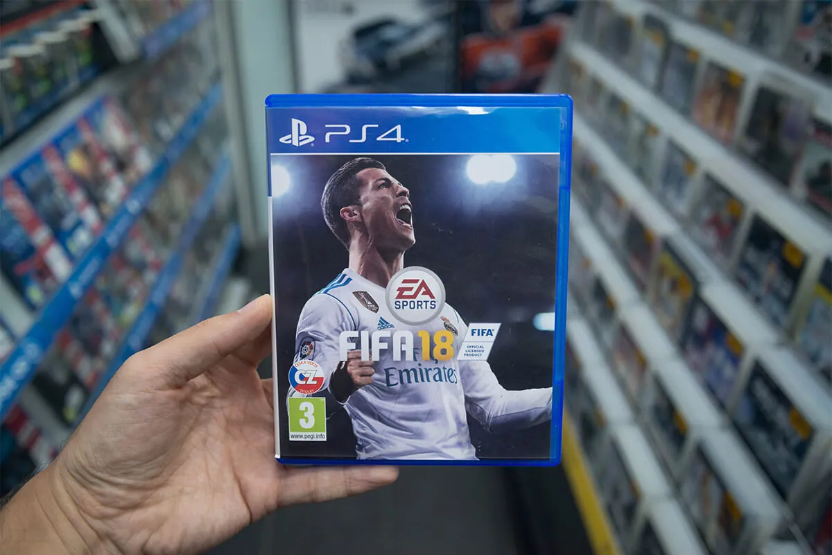 Man holding Fifa 18 videogame on Sony Playstation 4 console in store.