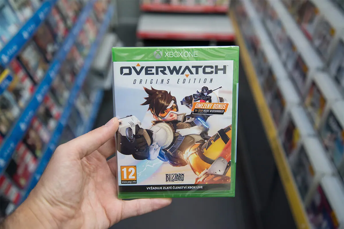 Man holding Overwatch videogame on Microsoft XBOX One console in store.